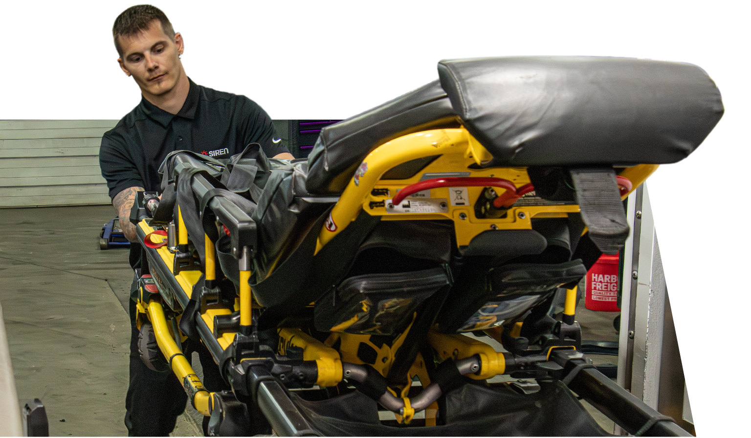 A paramedic operating a motorized ambulance stretcher loading system.